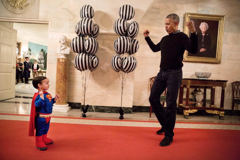 President Barack Obama flexes biceps with Superman Walker Earnest in the Lower Cross Hall of the White House, prior to welcoming local children to trick-or-treat for Halloween at the South Portico, Oct. 31, 2016. Walker is the son of Press Secretary Josh Earnest. (Official White House Photo by Pete Souza)