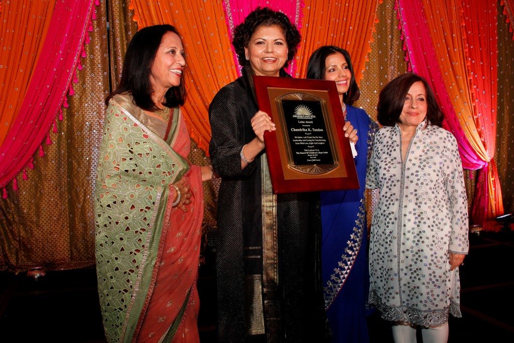Chandrika Tandon receives the Lotus Award, flanked by Maya Rajani, Children's Hope India president, Tinku Jain, master of ceremonies, and Lavina Melwani, Children's Hope India co-founder. 